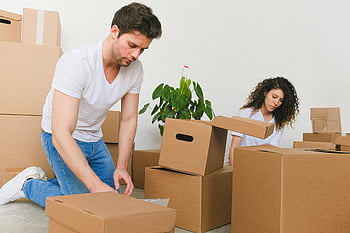 Mann und Frau packen Kisten, junges Paar beim Auspacken, neues Zuhause, gemütlicher Raum, Umzugstag, Kartons, Innenszene, Wohnkultur, Lebensstil, einziehen, Boxen auspacken