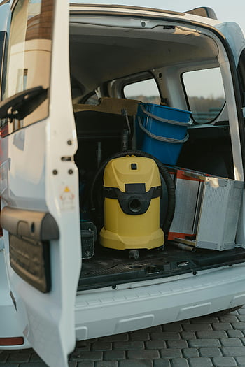 cleaning van, yellow and black car door, cargo area, vacuum cleaner, cleaning equipment, blue buckets, organized van, service vehicle, cleaning supplies, van interior, utility van