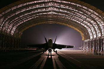 fighter jet, illuminated hangar, night scene, dramatic scene, military aircraft, silhouetted jet, aviation photography, hangar interior, night photography, fighter plane, military hangar