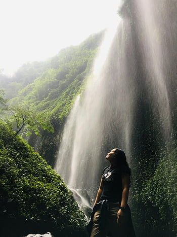 cascata di madakaripura, colpo basso angolo, donna in piedi, vegetazione lussureggiante, Serena cascata, fotografia naturalistica, fotografia di viaggio, avventura all'aria aperta, bellezza naturale, destinazione del viaggio, fotografia a cascata