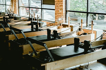 στούντιο Pilates, μηχανές αναμόρφωσης, μεγάλα παράθυρα, φωτεινό στούντιο, γυμναστήριο, καφέ και μαύρο, μηχανές άσκησης, εσωτερική γυμναστική, χώρο προπόνησης, παράθυρα στούντιο