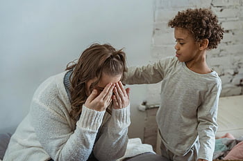 Černý syn, uklidňující matka, zoufalá matka, útulný obývací pokoj, mladý kluk, emocionální podpora, Rodinný okamžik, Emocionální spojení, matka a syn, Komfortní gesto, vnitřní scéna