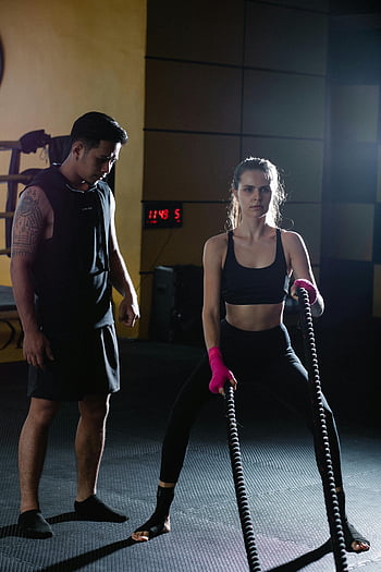 Latin American coach, sportswoman, battle ropes, personal trainer, gym setting, intense exercise, fitness training, workout session, athletic woman, fitness instructor, gym workout