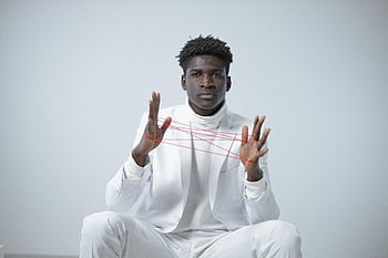 man in white clothes, red string art, minimalistic background, elegant portrait, white suit, string manipulation, artistic expression, modern art, creative photography, studio shot, contemporary art