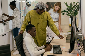 Multikulturelles Team, modernes Büro, kollaborative Arbeit, Computers, Unterlagen, Büroeinstellung, vielfältige Belegschaft, professionelles Umfeld, Zusammenarbeit am Arbeitsplatz, Teaminteraktion, Bürotechnologie