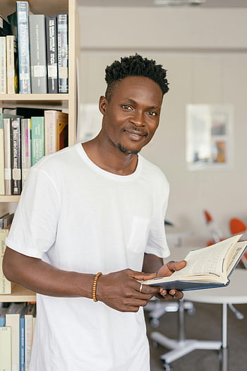 رجل يرتدي قميصا أبيض،  كتاب مفتوح،  يبتسم الشاب،  مكتبة،  رف الكتب،  قراءة،  التعليم،  دراسة،  لباس غير رسمي،  إعداد داخلي،  المثقف