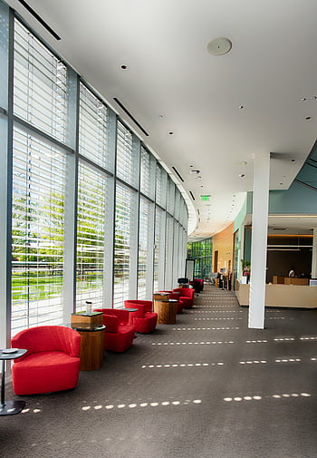 red sofa chairs, glass wall, building interior, contemporary lobby, natural light, expansive windows, red lounge chairs, spacious lobby, modern interior, office lobby, indoor seating area