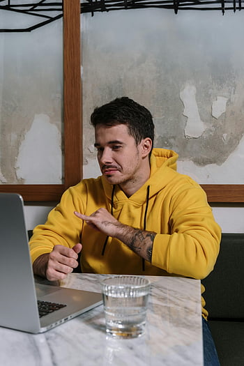 yellow hoodie, man, laptop, sign language, indoors, young man, working, computer, casual, workspace, communication