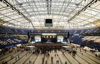 crowded people, live concert, indoor arena, prominent stage, daytime event, wide shot, large crowd, concert venue, music event, audience gathering, big stage