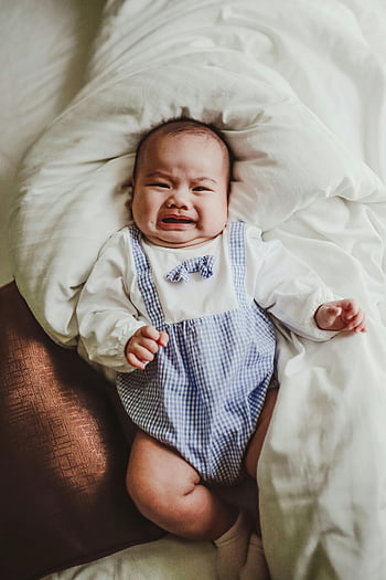 crying baby, blue romper, white sheets, baby on bed, emotional baby, baby lying down, baby expression, baby in bed, baby crying, baby in blue, baby on pillow