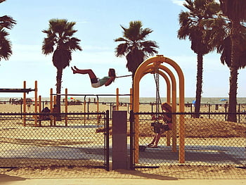 woman playing swing, beach, Venice Beach, Los Angeles, California, kids enjoying swing, palm trees, playground, outdoor activities, summer fun, family time