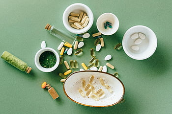 colocação plana, medicamentos alternativos, suplementos de ervas, suplementos farmacêuticos, tigelas de cerâmica, fundo verde, vista do topo, vitaminas, pílulas, cápsulas, remédios naturais