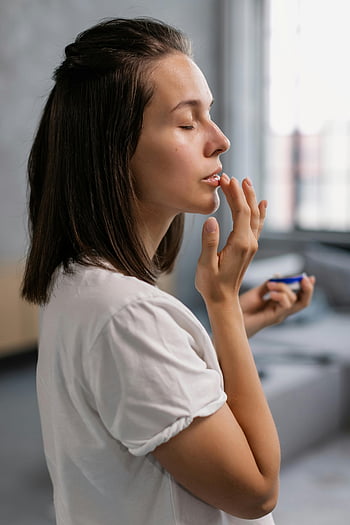 Žena aplikující balzám, boční pohled, balzám na rty, zavřené oči, klidný okamžik, uvnitř, Rutina krásy, péče o kůži, osobní péče, Přírodní krásy, klidná atmosféra