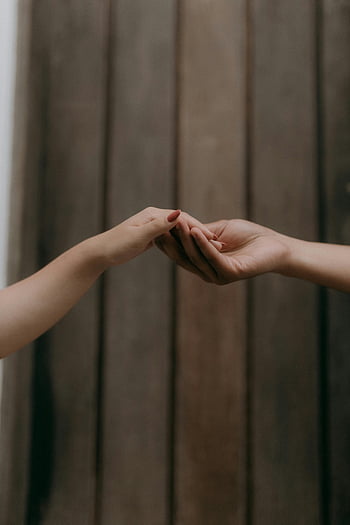 hands reaching out, minimalist image, wooden background, soft touch, close-up hands, connection, human interaction, gentle touch, two hands, simplicity, intimacy