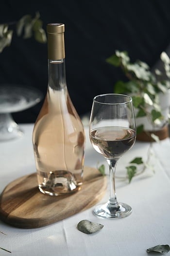 bouteille de vin, verre de vin, plateau en bois, fond de verdure, photo en gros plan, vin blanc, réglage de la table, présentation élégante, table à manger, verrerie, dégustation de vins