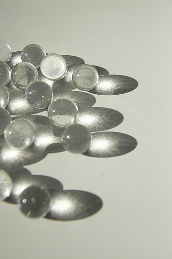 glass balls, shadows, white table, daylight, clear glass spheres, intricate shadows, bright table surface, minimalist decor, glass spheres, decorative glass, glass decor