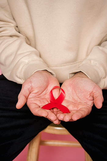 červenou stuhou, AIDS povědomí, Podpora zdravotní péče, ruce hospodářství, detailní fotografie, Červený symbol, Symbol AIDS, Propagace zdravotní péče, stuha symbol, Stuha AIDS, Stuha vědomí