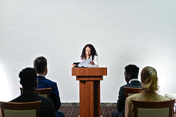 スピーチをする女性、 自信のあるスピーカー、 多様な聴衆、 会議室、 人前で話す、 プロのプレゼンテーション、 ビジネスイベント、 視聴者のエンゲージメント、 演壇に立つ講演者、 フォーマルイベント、 リーダーシップスキル