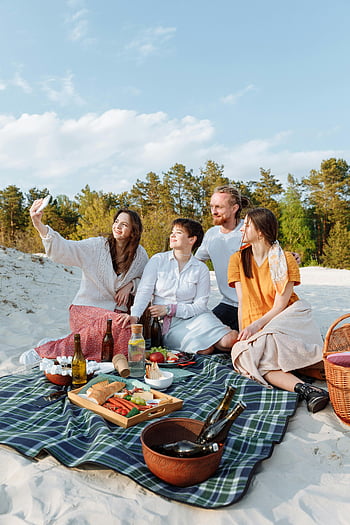 ビーチピクニック、 グループselfie、 晴れの日、 陽気な友達、 ピクニック毛布、 屋外の集まり、 フードスプレッド、 ビーチの設定、 夏の活動、 カジュアルな外出、 自然の背景