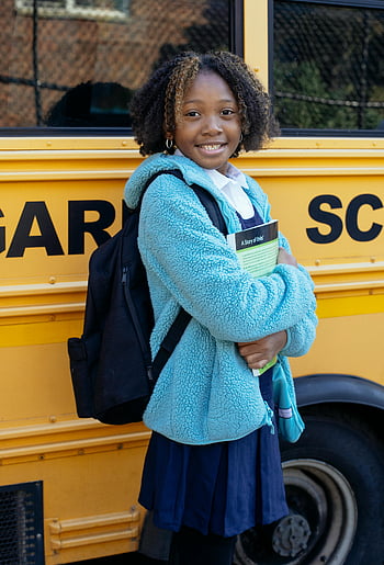 African American schoolgirl, cheerful young girl, backpack, yellow school bus, smiling, workbook, city street, school uniform, education, outdoor, student