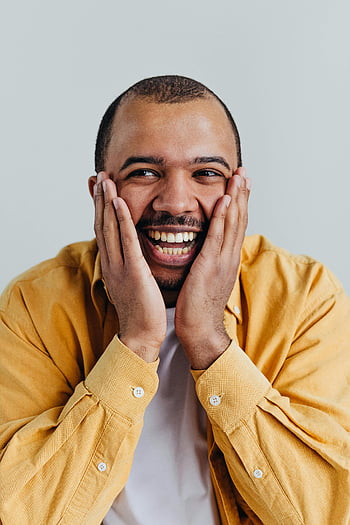 Afroamerikanermann, lächelnd, Hände im Gesicht, Studioaufnahme, glücklich, Porträt, gelbes Shirt, heiter, Studioportrait, schwarzer Mann, Studiofotografie