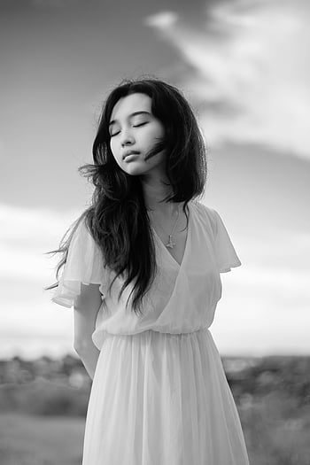 Donna asiatica consapevole, vestito elegante, campagna, sereno, calma, vestito bianco, ritratto all'aperto, occhi chiusi, giovane donna, bianco e nero, ambientazione pacifica