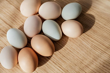 multicolored eggs, wooden table, fresh eggs, natural wooden surface, daylight, egg collection, colorful eggs, rustic table, farm fresh, natural eggs, egg variety