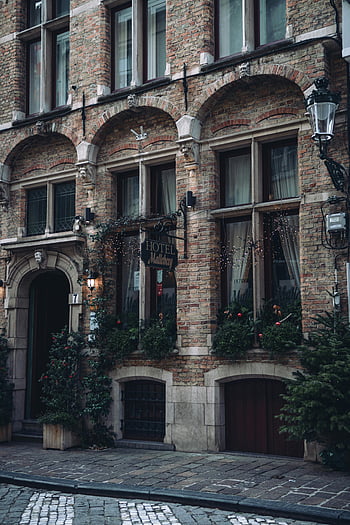 old brick building, city street, hotel facade, arched windows, greenery, quaint city, brick architecture, urban scene, historic building, street view, hotel sign