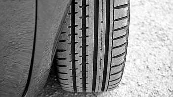 vehicle tire, tread pattern, gravel surface, detailed view, car tire, tire tread, close-up, automotive, road surface, tire detail, tire texture
