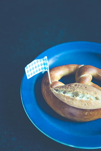 Bajor perec, kockás zászló, kék lemez, német konyha, fesztivál étel, sózott perec, Oktoberfest, hagyományos snack, európai élelmiszer, sült csemeg, rusztikus kenyér