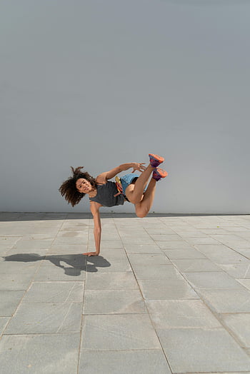 woman breakdancing, talented breakdancer, outdoor pavement, breakdance move, street dance, urban dance, female dancer, athletic performance, dance photography, dynamic pose, pavement dance
