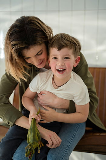 mother and son, happy family, indoor togetherness, toy dinosaur, smiling child, mother embracing son, family bonding, casual indoor scene, playful moment, family love, cozy home setting