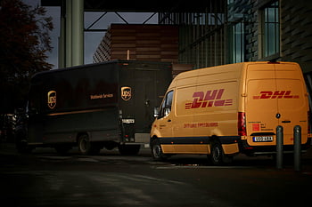 camion per la consegna della posta, Camion DHL, camion UPS, camion parcheggiati, Parcheggio notturno, costruzione moderna, operazioni logistiche, Servizi di consegna, Logistica urbana, scena notturna, Veicoli di consegna