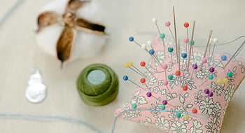needle pillow, colorful pins, thread spool, sewing workspace, crafting inspiration, sewing tools, pincushion, sewing materials, crafting supplies, sewing table, thread roll