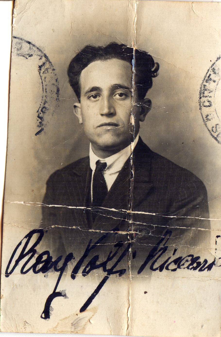 vintage photo, black and white, man in suit, formal portrait, old document, signature, aged paper, creased image, historical photograph, retro style, male subject