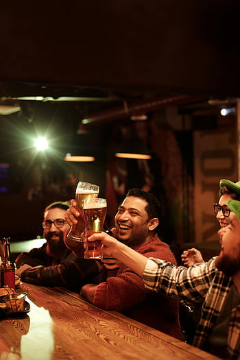 giorno di San Patrizio, bar, gruppo di amici, godersi le bevande, risata, pub, Celebrazione indoor, bicchieri di birra, Atmosfera festosa, ritrovo sociale, impostazione casuale