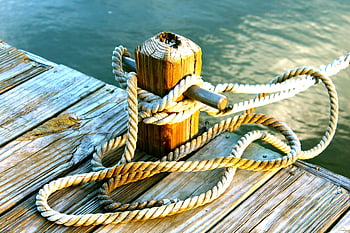 brown wooden dock, post, brown rope, coiled rope, wooden dock post, ocean, detailed view, dock, rope knot, wooden pier, water edge