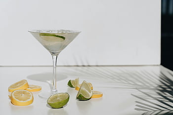 owoce cytrusowe, szklanka do drinków, plasterki limonki, plastry cytryny, orzeźwiający koktajl, Minimalistyczne tło, jasne tło, Plasterki cytrusów, dekoracja koktajli, tropikalny napój, ozdoba z owoców