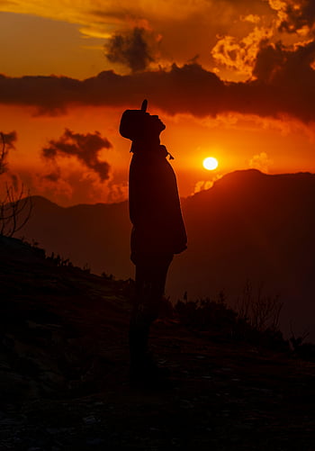 sunset silhouette, man silhouette, mountain peak, vibrant sunset, backlit silhouette, outdoor photography, nature scene, sunset landscape, mountain sunset, dramatic sky, sunset photography
