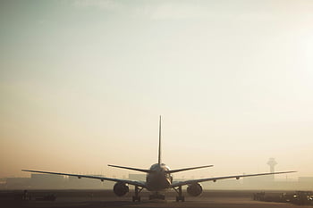 white and gray airplane, misty morning, plane on runway, hazy sky, air travel, ambiance, airport scene, aviation, commercial aircraft, travel photography, runway view