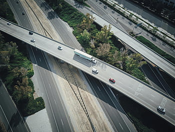 highway intersection, aerial shot, vehicles in motion, asphalt highways, high-angle view, traffic flow, urban infrastructure, road network, transportation system, car movement, truck travel