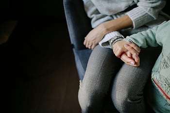 moeder en kind, handen vasthouden, samen zitten, Warmte en verbinding, grijs shirt met lange mouwen, blauw shirt met lange mouwen, close-up foto, familieband, intiem moment, moederschap, kinderopvang