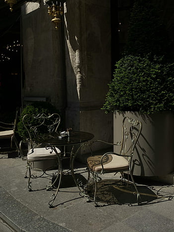 outdoor café, ornate iron chairs, city street corner, classic-looking chairs, table, charming, outdoor seating, urban setting, street furniture, decorative chairs, cityscape