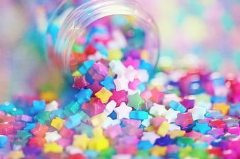 multi colored candies, clear glass jar, vibrant close-up, colorful star-shaped candies, rainbow hues, spilling jar, candy jar, star candies, colorful candies, close-up photo, rainbow colors