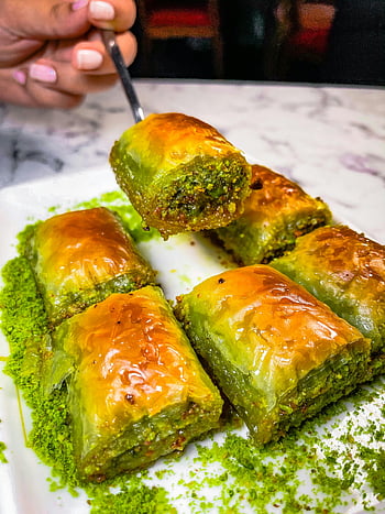 baklava slices, pistachio baklava, white ceramic plate, close-up baklava, rich flavors, delicious baklava, textures baklava, pistachio dessert, sweet pastry, traditional dessert, baklava plate