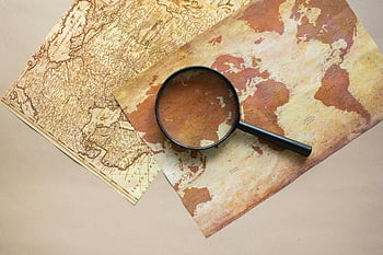 vintage world map, magnifying glass, exploration themes, beige paper, vintage maps, map exploration, world map, magnifying glass on map, exploration tools, map details, map study