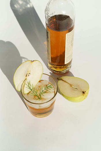 pear calvados, chilled pear cocktail, brandy, dill sprig, refreshing taste, pear slices, glass of pear calvados, bottle of brandy, cocktail with brandy, pear drink, dill garnish