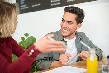 kvinne snakker, Mann, positiv diskusjon, koselig kafé, unge voksne, nyter drikke, innendørs innstilling, tilfeldig samtale, vennlig samhandling, sosialt møte, juice flaske