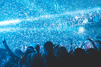 concert, people having fun, vibrant nightclub, lively crowd, confetti, blue lights, nightlife, party atmosphere, music event, celebration, entertainment