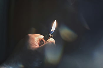 hand holding lighter, igniting lighter, flame, dimly lit environment, close-up, hand, lighter, fire, dark background, focus on flame, smoke
